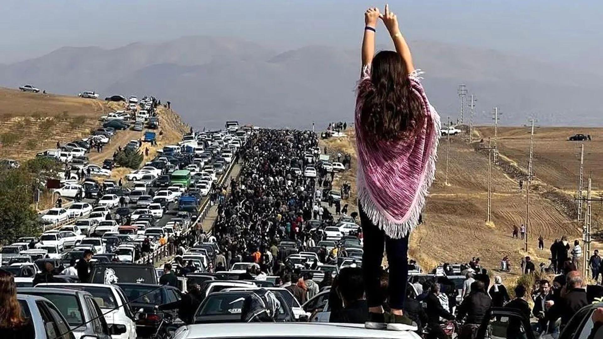 Eine Frau steht bei einem Protest im Iran auf einem Auto.