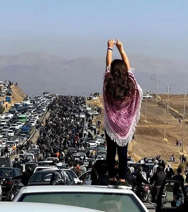 Eine Frau steht bei einem Protest im Iran auf einem Auto.