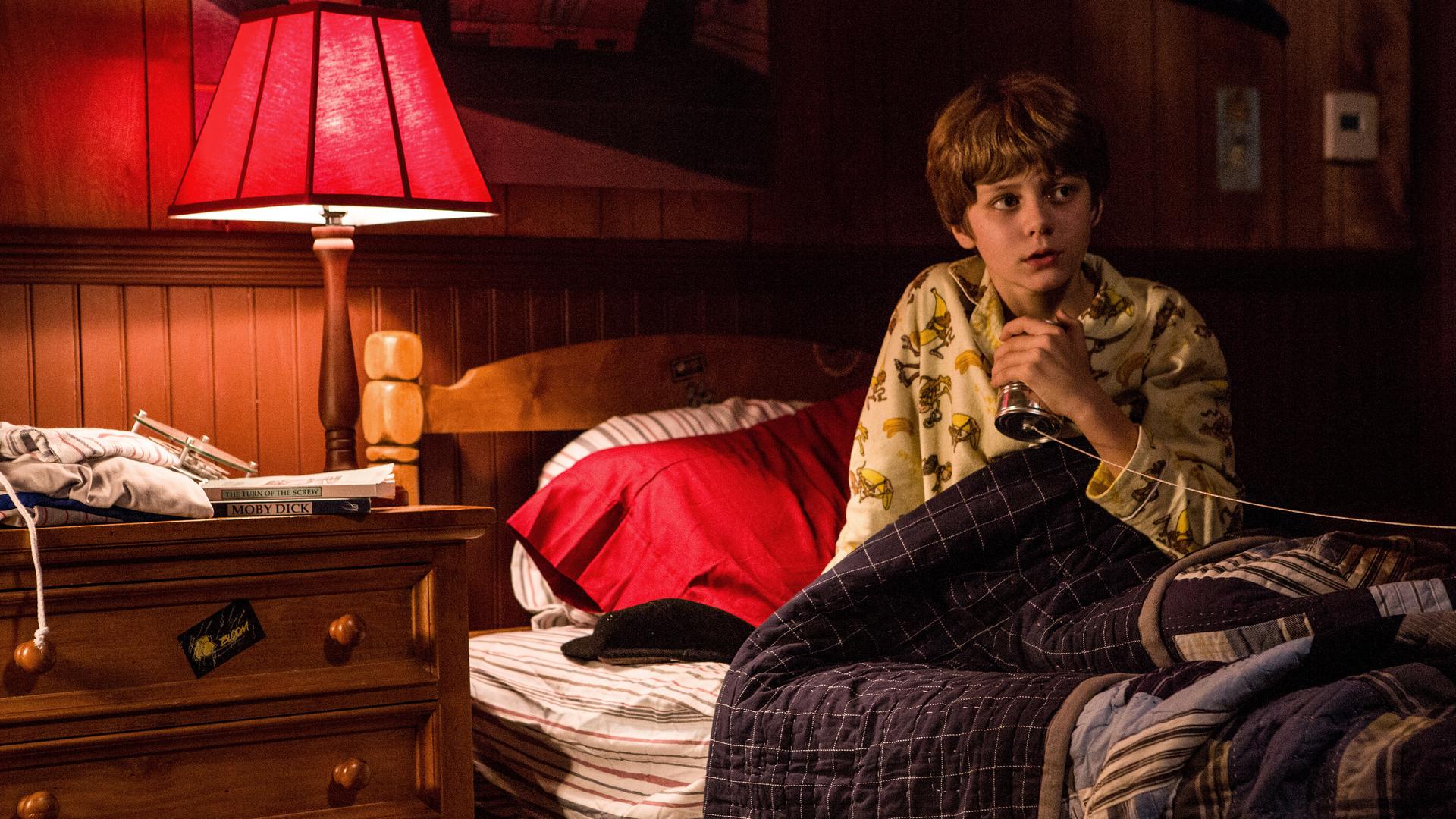 "Insidious: Chapter 2": Dalton (Ty Simpkins) sitzt ängstlich in seinem Bett und umklammert sein selbst gebasteltes Dosentelefon.