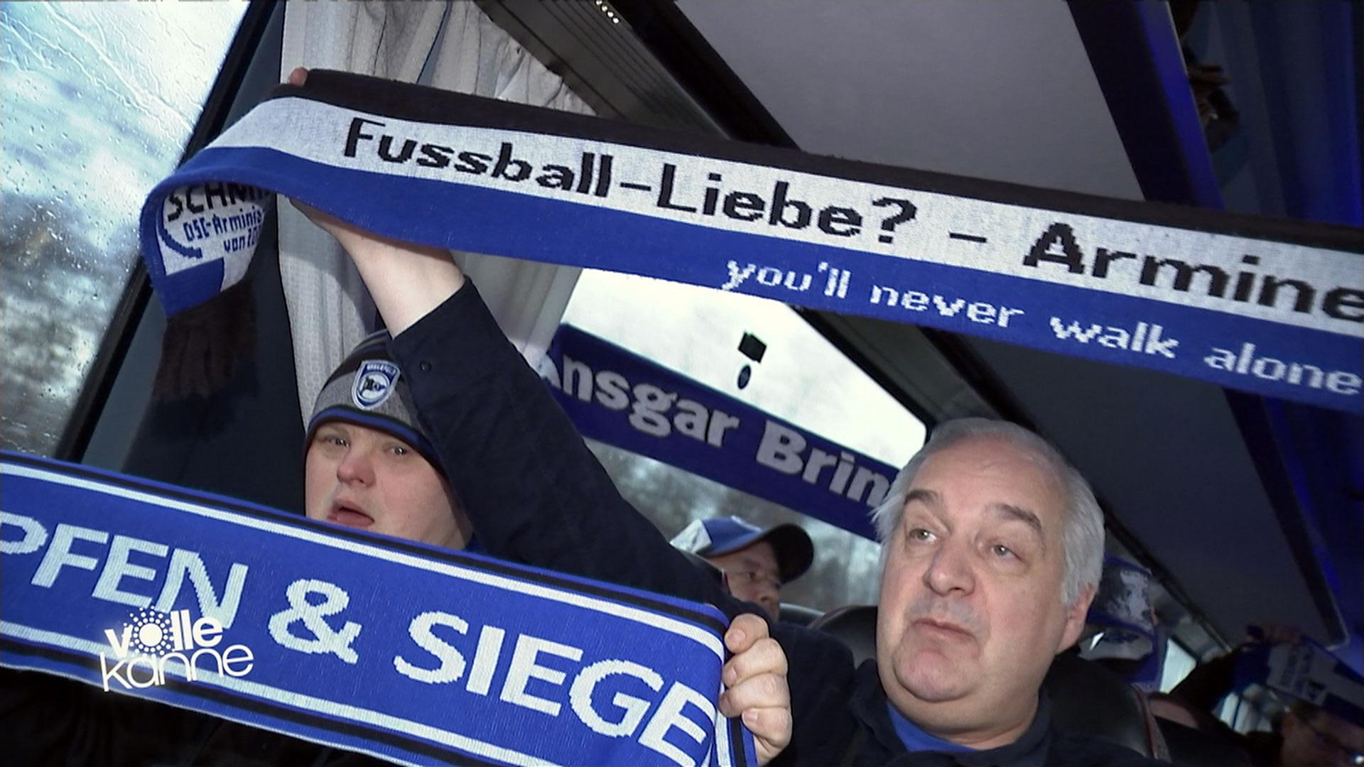 Mitglieder des integrativen Fanclubs "Arminen-Schmiede" aus Bielefeld halten Fan-Schals hoch