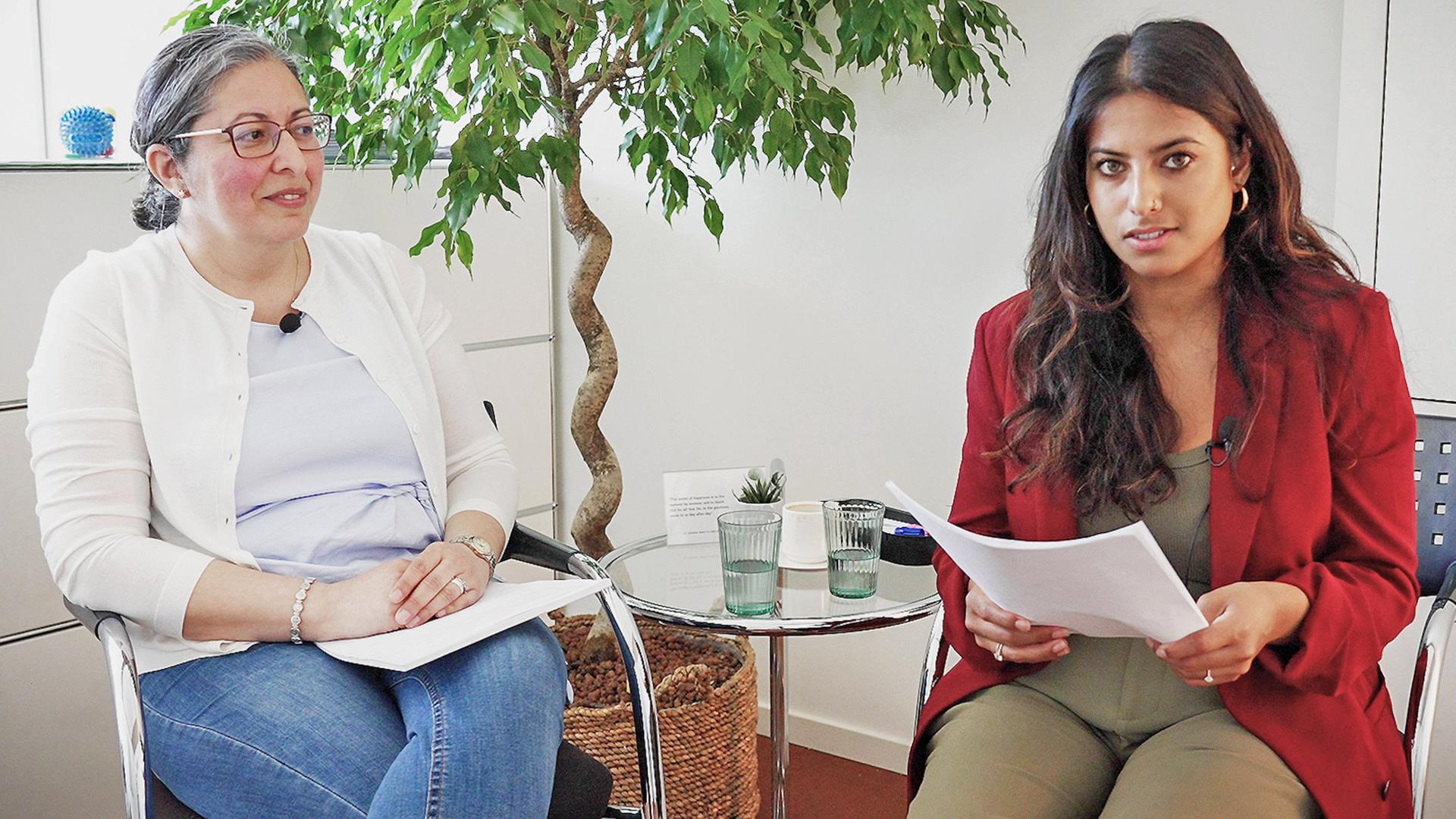 Zwei Frauen sitzen neben einem Glastisch