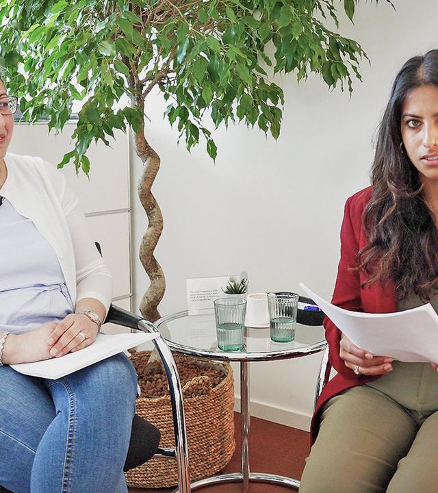 Zwei Frauen sitzen neben einem Glastisch