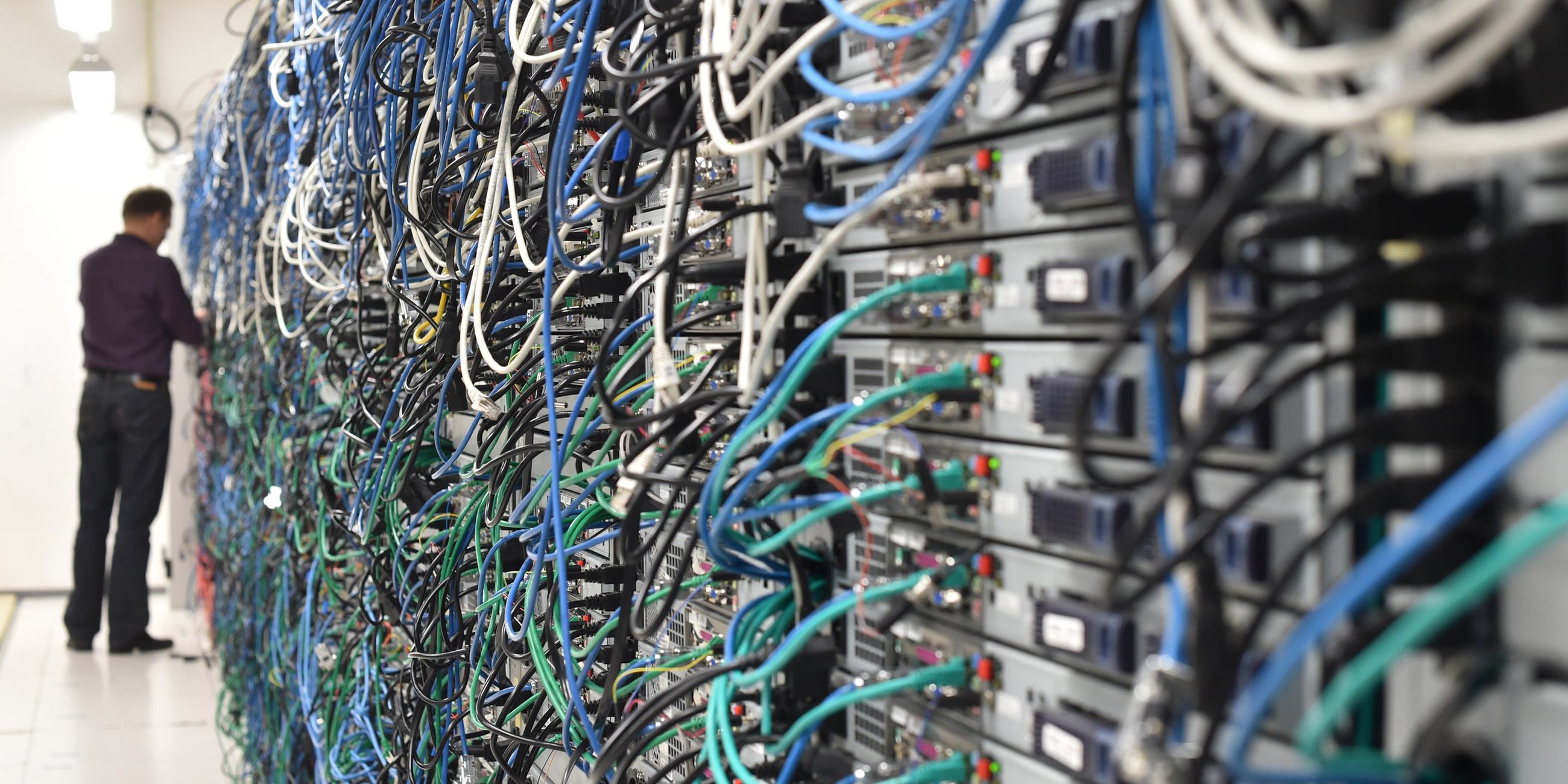Innenansicht des Serverraums eines Rechenzentrums mit zahlreichen Kabeln und Serverschränken