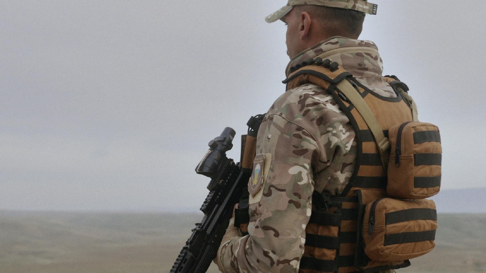 "Irak - Zerstörung eines Landes - Jagd auf den Diktator": Ein Soldat in Tarnuniform hält eine Waffe in der Hand und blickt auf eine Landschaft unter sich.