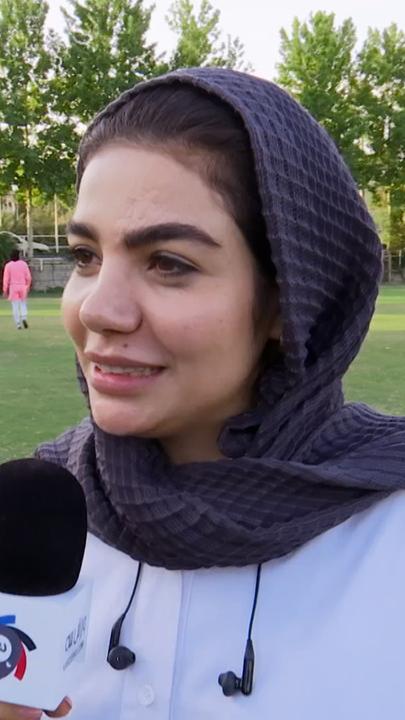 Eine iranische Sportjournalistin steht auf einem Fußballplatz und gibt ein Interview
