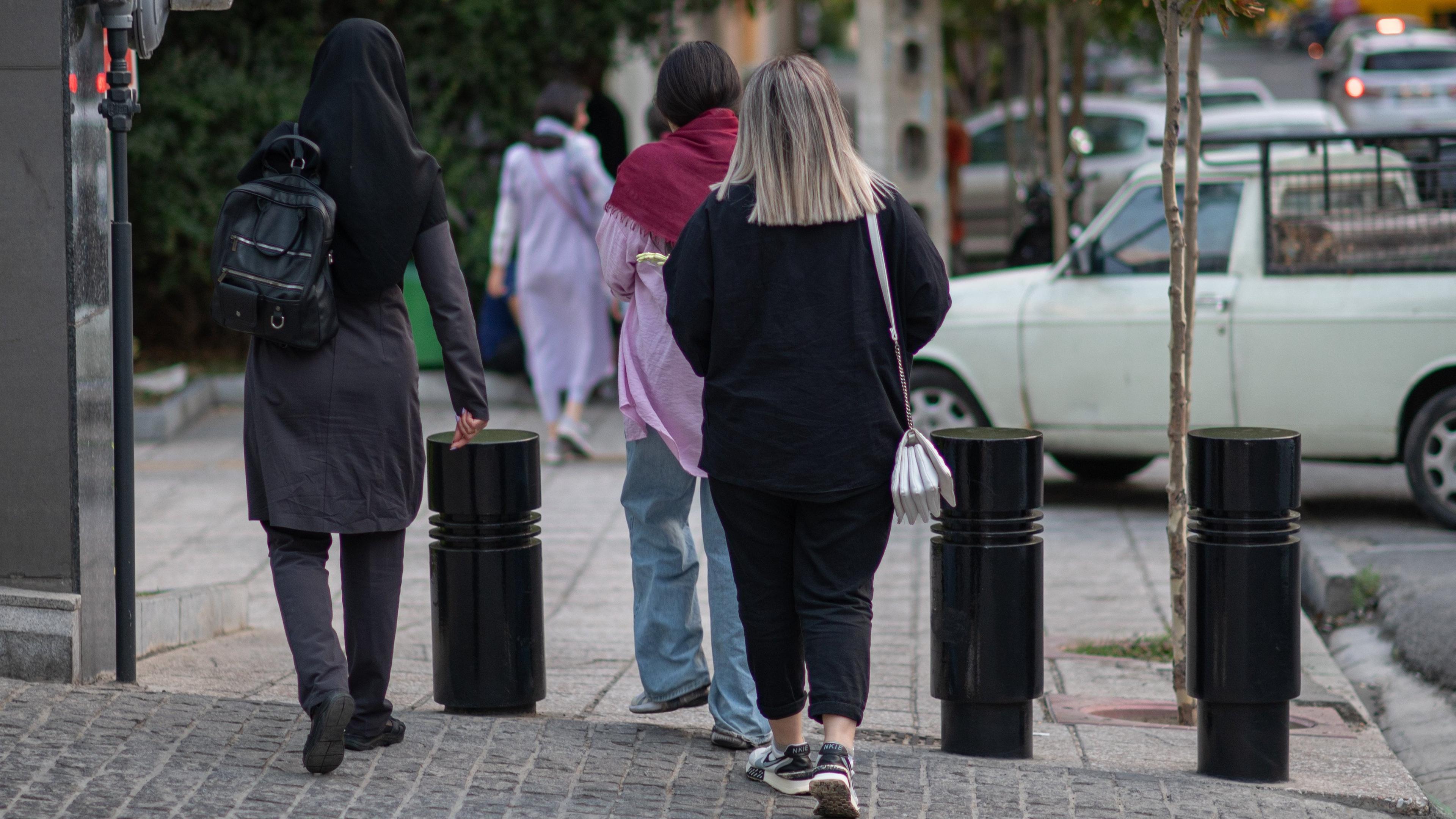 25.07.2023, Iran, Teheran: Frauen mit und ohne Kopftuch gehen eine Straße in der iranischen Hauptstadt entlang.