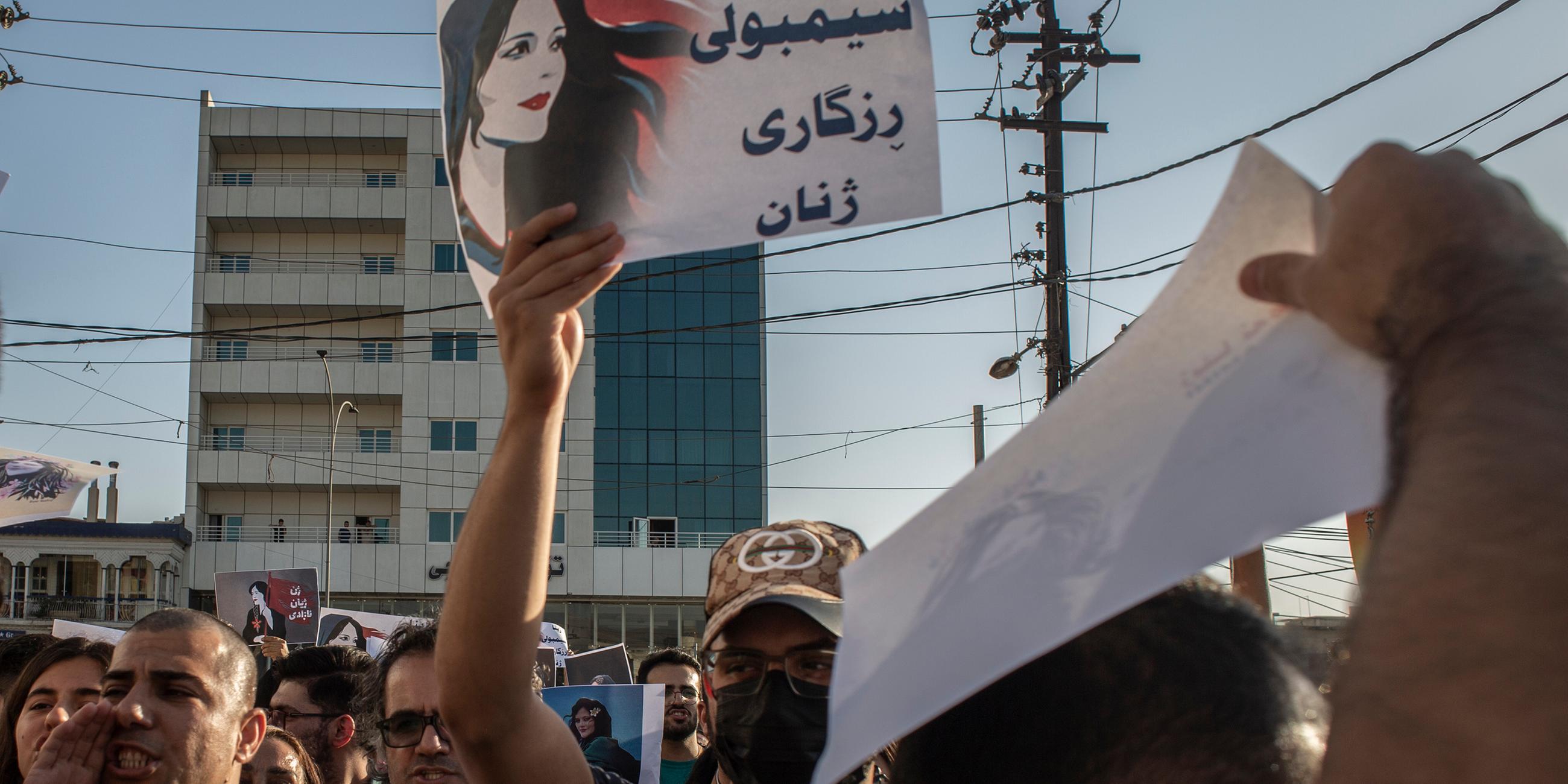 Menschen protestieren und halten Schilder um den Tod von Mahsa Amini zu verurteilen
