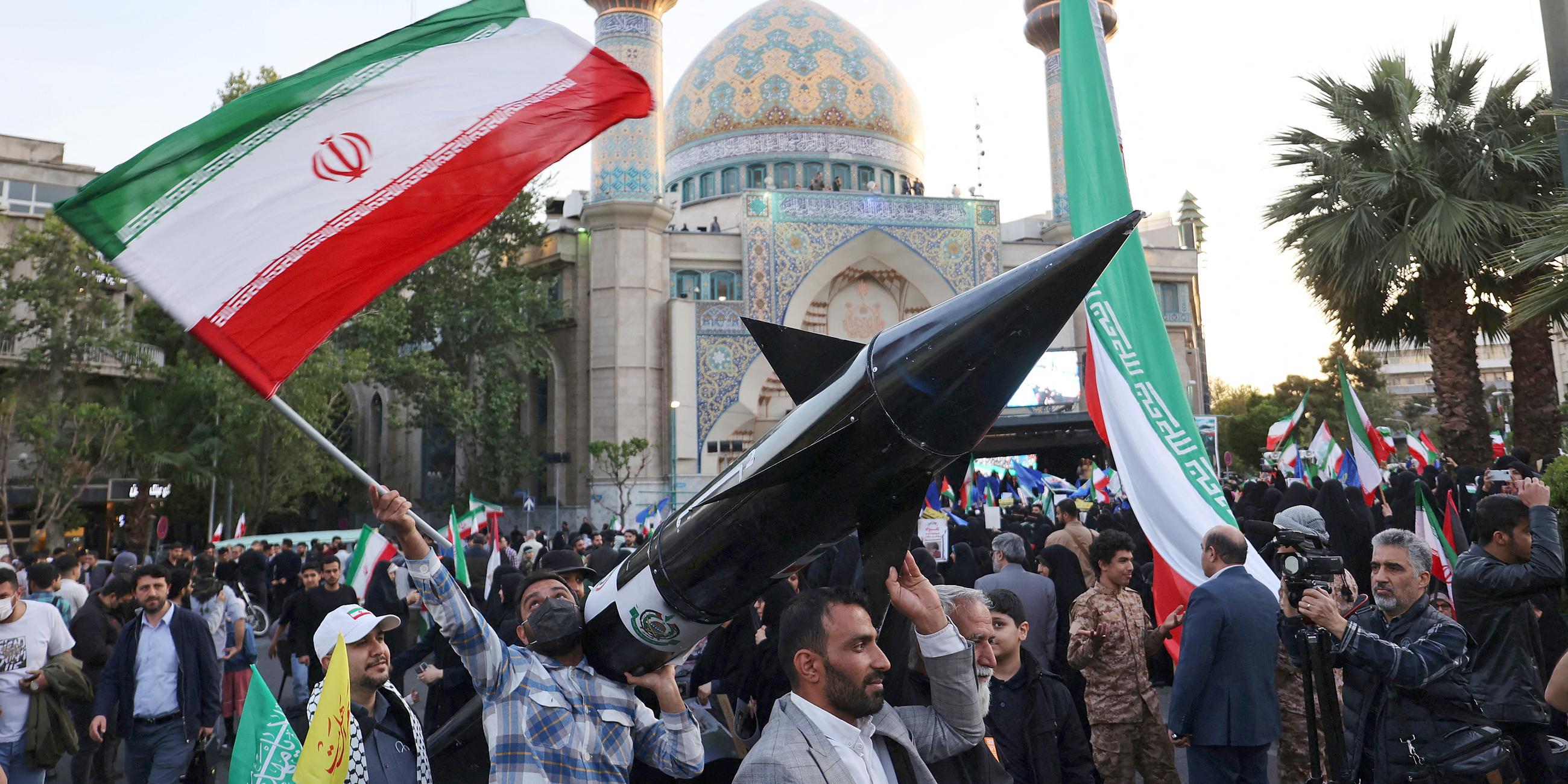 Iraner tragen ein Modell einer Rakete während einer Feier nach dem Angriff der IRGC auf Israel in Teheran (Iran), aufgenommen am 15.04.2024