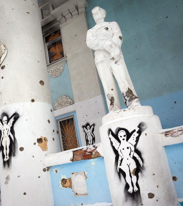 Statue und Säulen mit Einschusslöchern im Inneren des zerstörten Kulturhauses