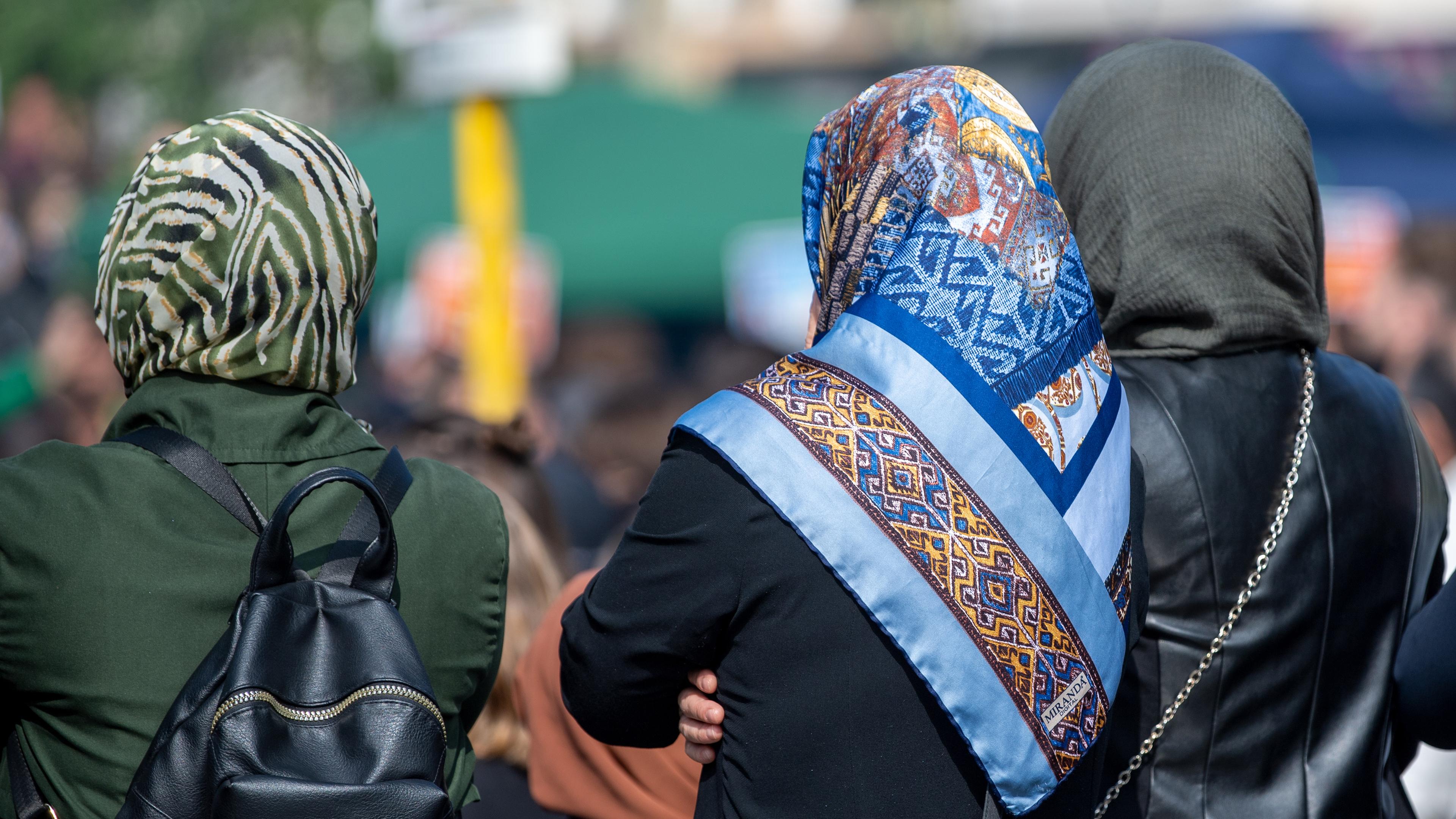 Zu sehen sind drei Frauen in Berlin von hinten; alle sind mit Kopftuch bedeckt.
