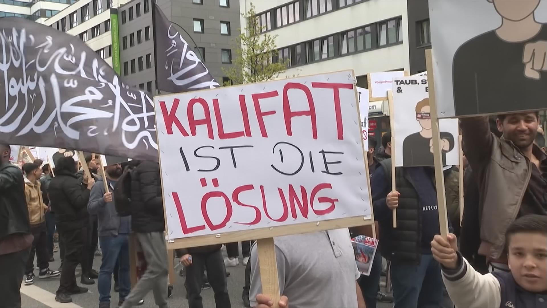 Demonstraten mit Plakat mit Aufschrift "Kalifat ist die Lösung".