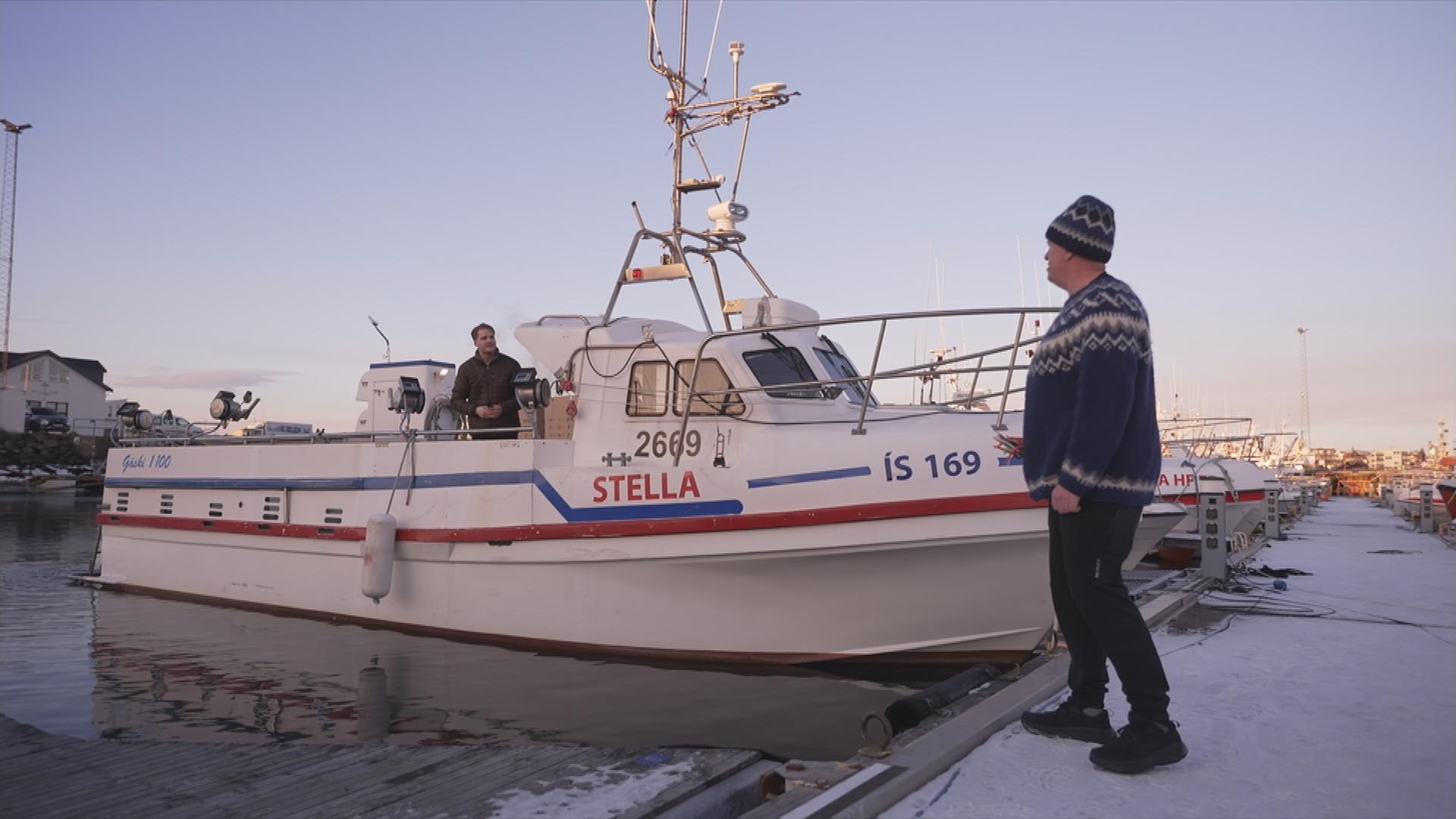 Mann vor einem Fischerboot in Island