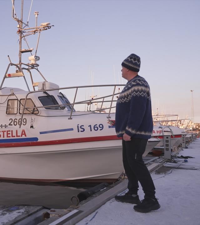 Mann vor einem Fischerboot in Island