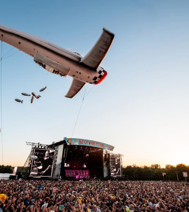 Ein riesiger Flugzeug-Luftballon fliegt über die Menge vor der Festivalbühne.
