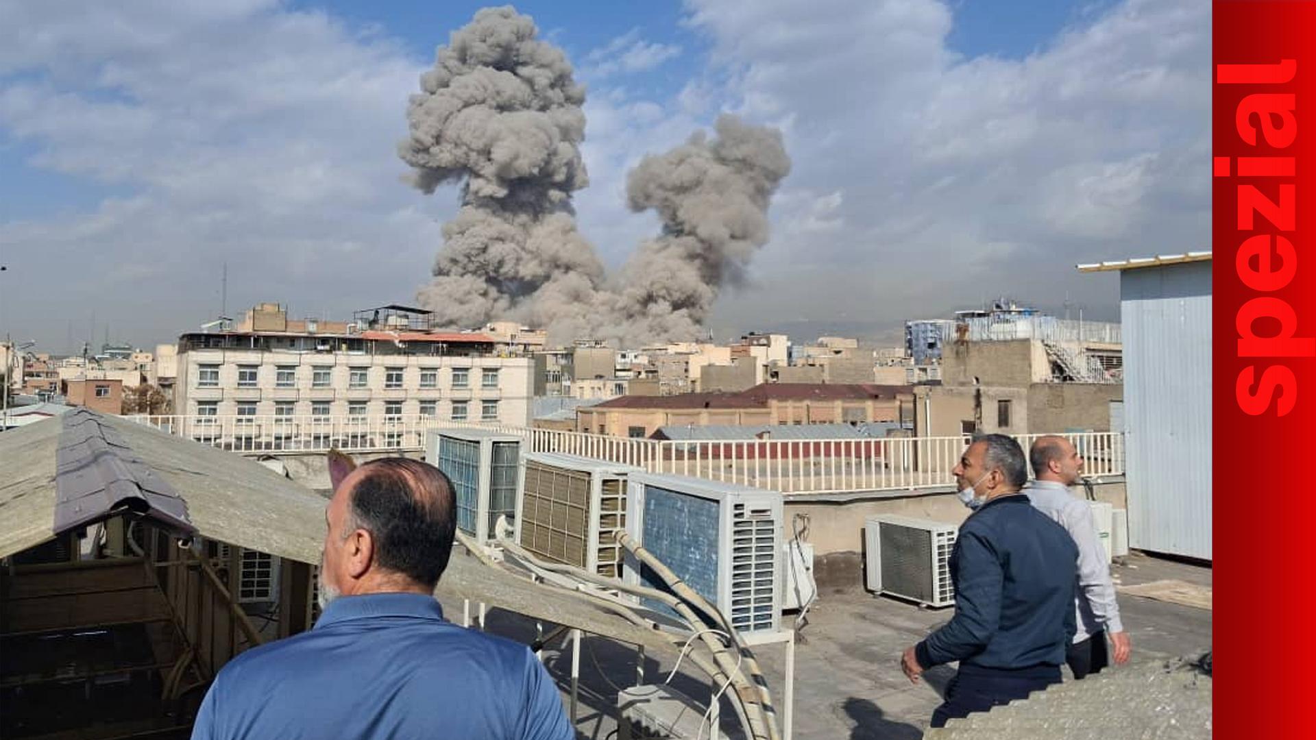 Menschen beobachten Rauch nach einer Explosion in Teheran.