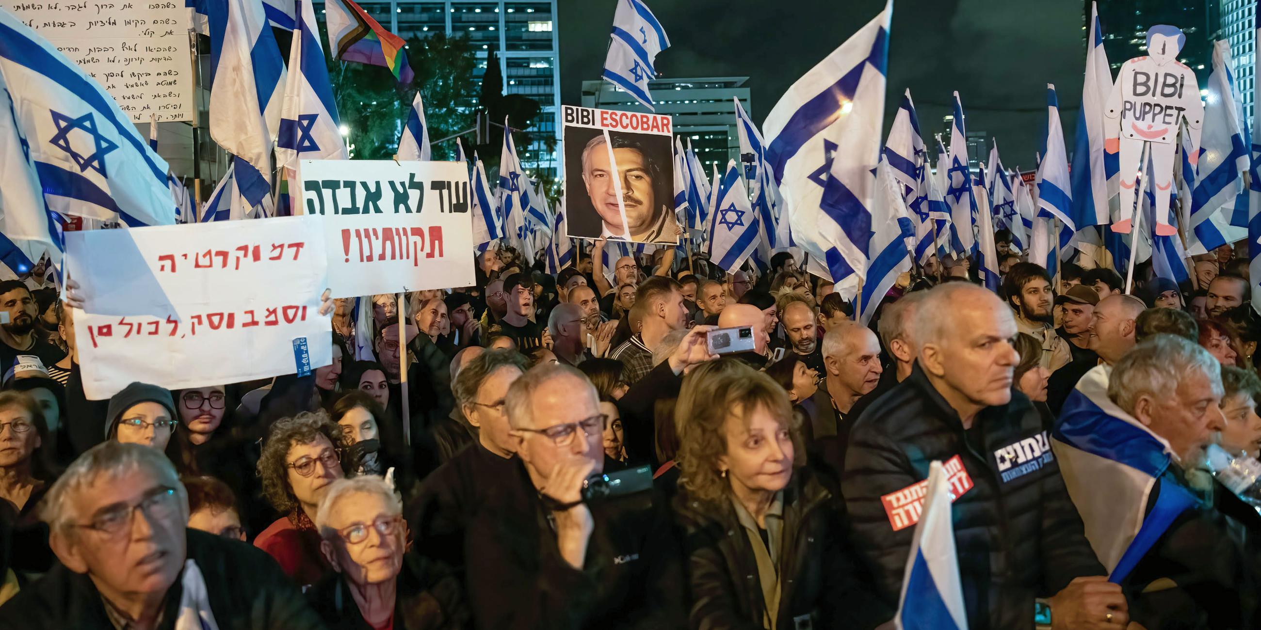 Demonstranten schwenken während einer Demonstration gegen die Justizreform israelische Fahnen neben einem Plakat mit dem Foto von Benjamin Netanjahu