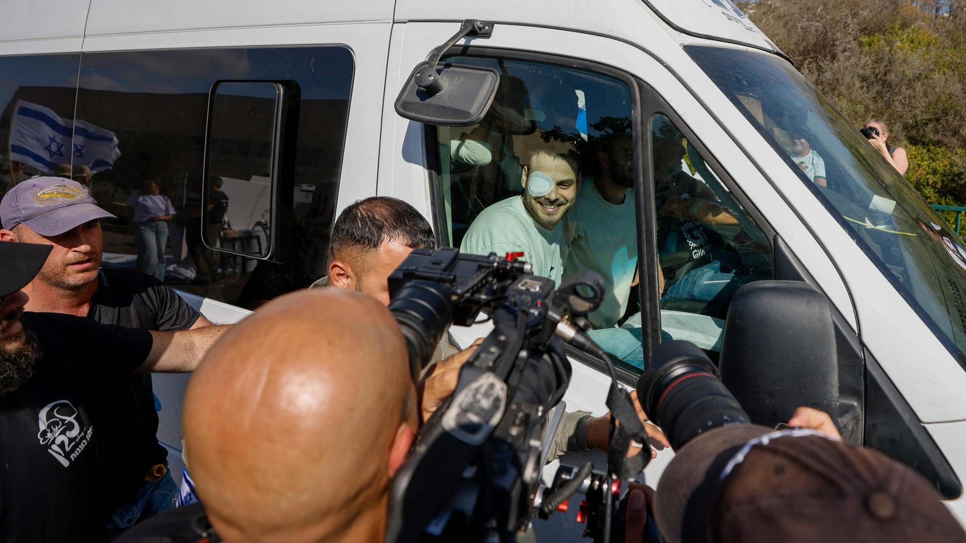 Ein weißer Transporter, in dem mehrere Männer sitzen und herausschauen wird von Kameraleuten und Fotografen belagert.