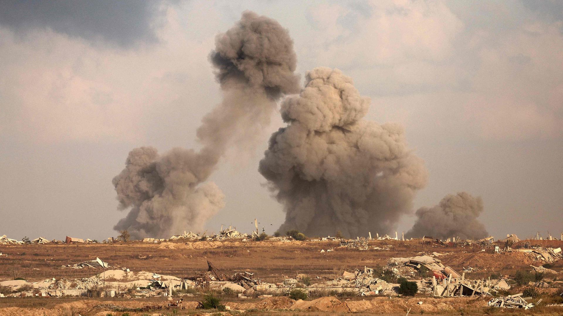 Eine Totalaufnahme einer zerstörten Landschaft in Gaza, Rauch steigt herab.