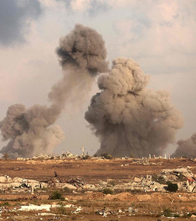 Eine Totalaufnahme einer zerstörten Landschaft in Gaza, Rauch steigt herab.