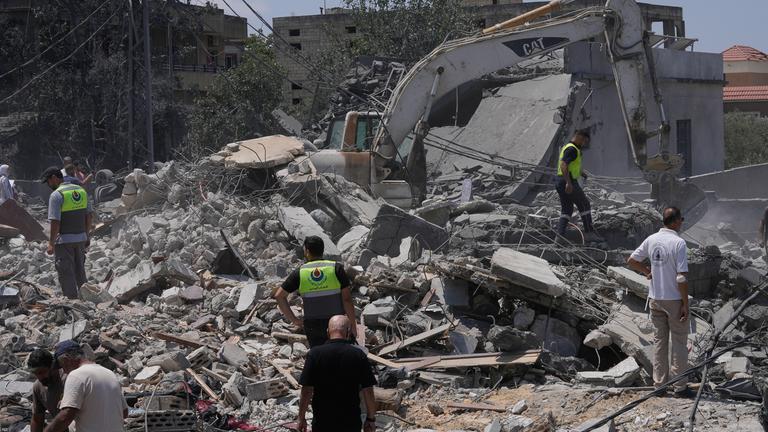 Menschen und Rettungskräfte versammeln sich vor einem zerstörten Haus, das von einem israelischen Luftangriff getroffen wurde. 