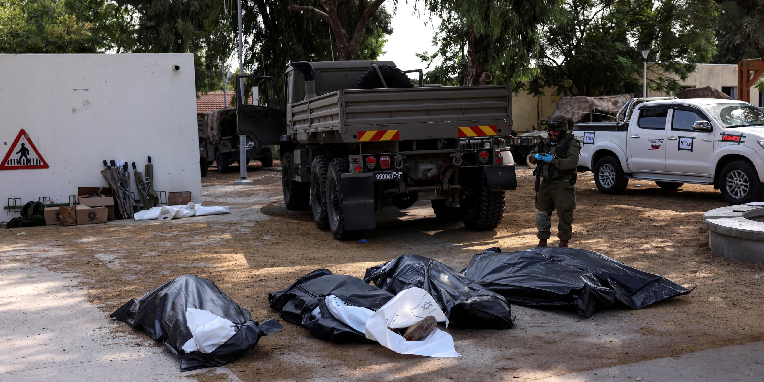 Bodies of victims of an attack, following a mass infiltration by Hamas gunmen from the Gaza Strip, lie on the ground in Kibbutz Kfar Aza, in southern Israel, October 10, 2023. 