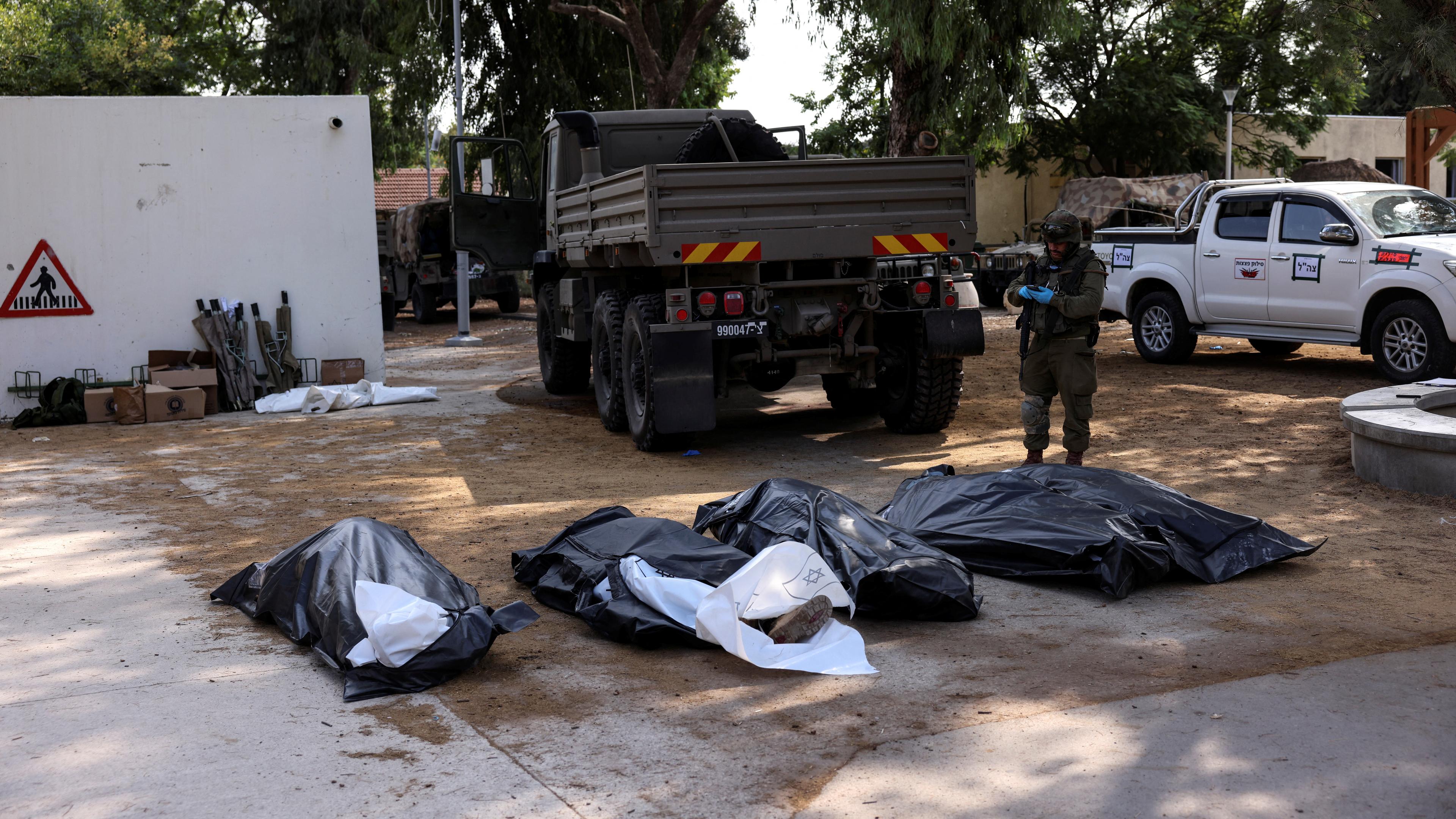 Bodies of victims of an attack, following a mass infiltration by Hamas gunmen from the Gaza Strip, lie on the ground in Kibbutz Kfar Aza, in southern Israel, October 10, 2023. 