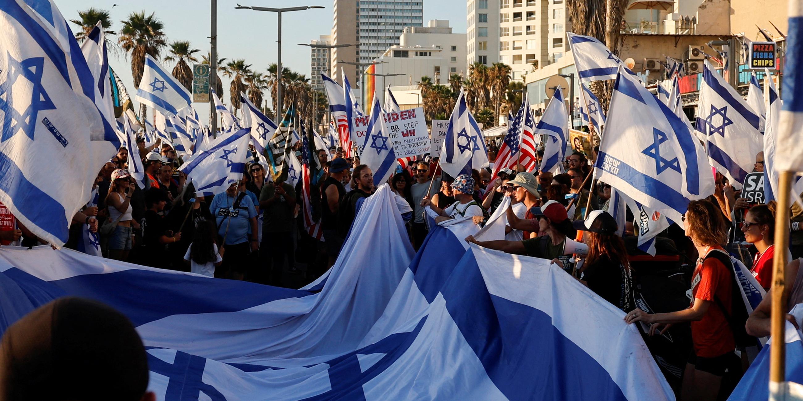 Menschen protestieren und halten israelische Flaggen am 18.07.2023 in Tel Aviv.