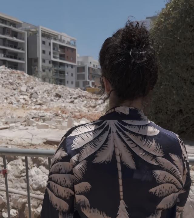 Mutter schaut auf zerstörtes Haus in Israel