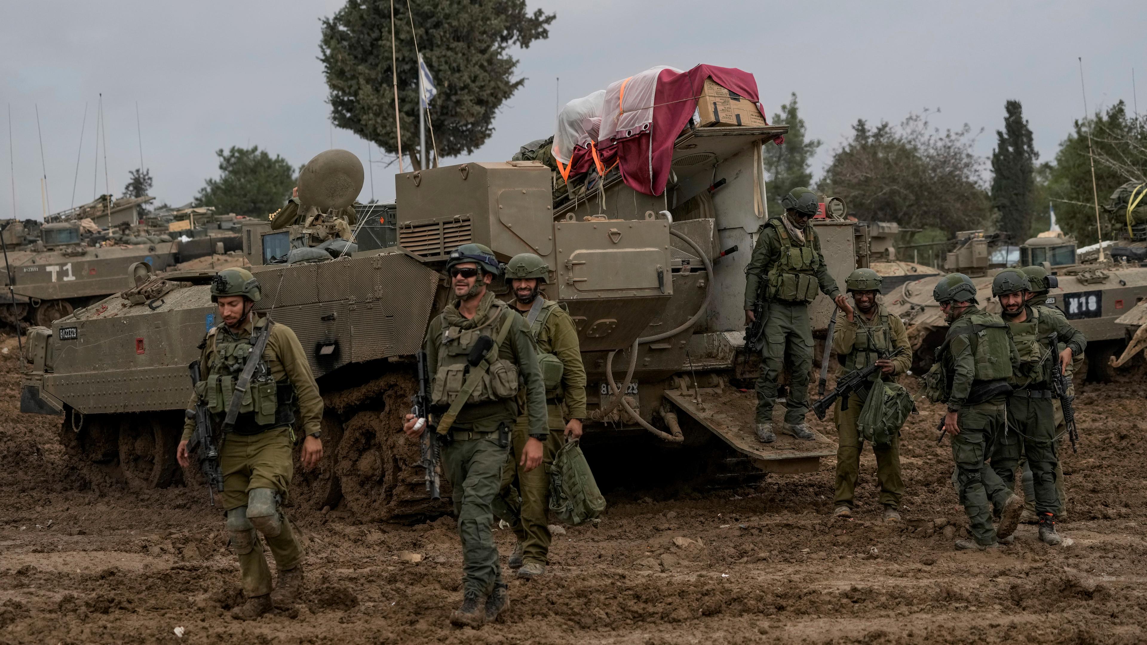 Beim Nahostkonflikt stehen und gehen israelische Soldaten vor einem Panzer.