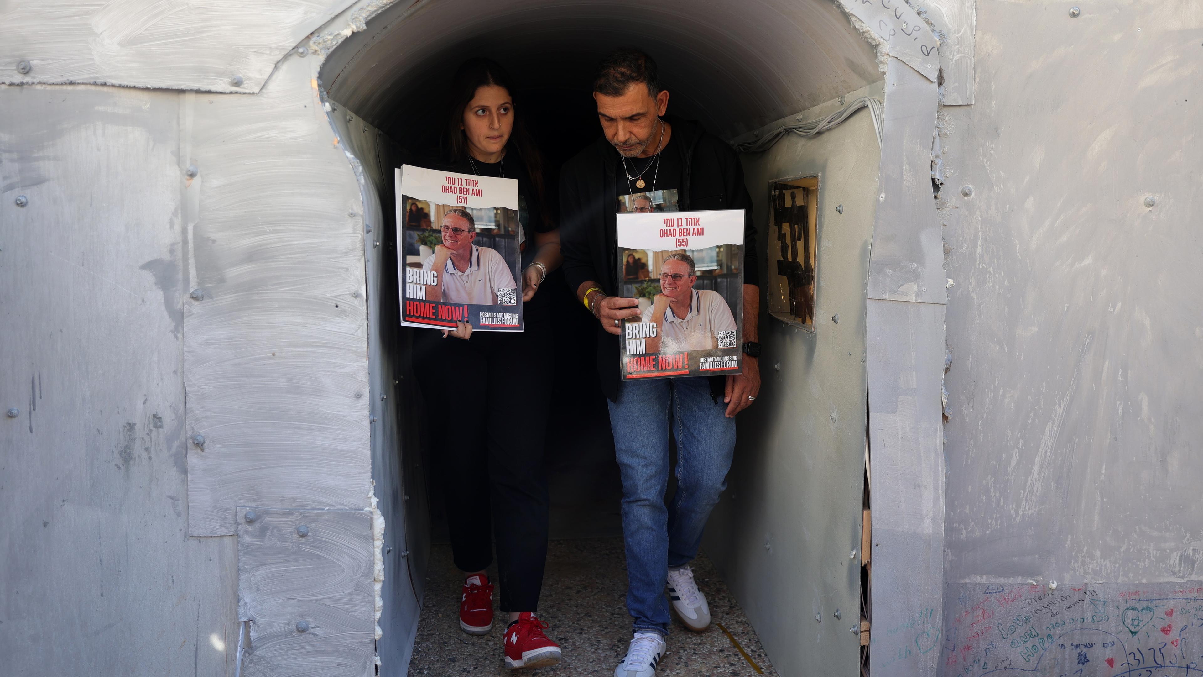 Zwei Menschen stehen im Nachbau eines Tunnels und halten Vermissten-Plakate hoch.