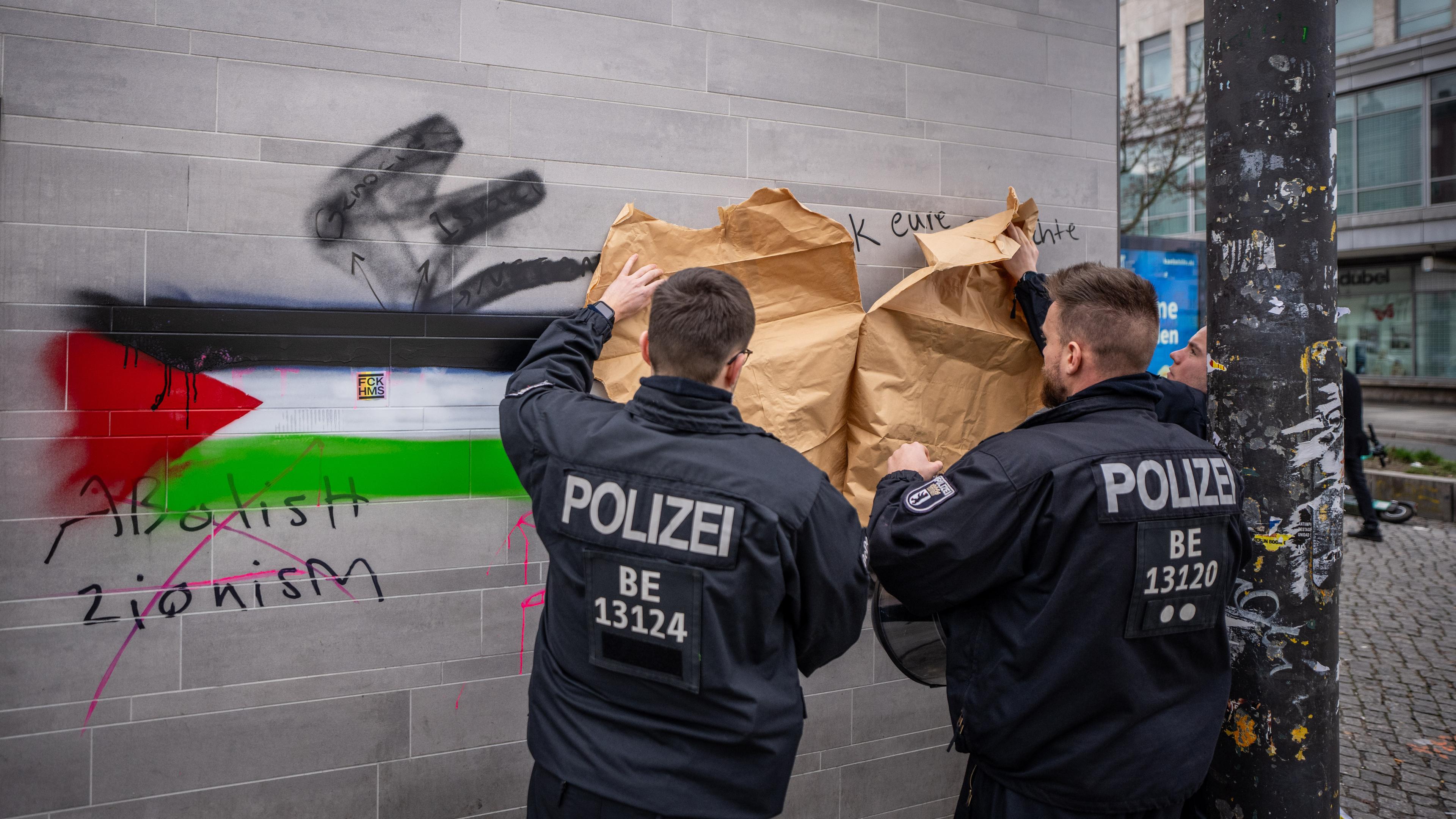 Polizisten kleben israelfeindliche Schmiererein am Hermannplatz in Berlin-Neukölln ab. (Archiv)