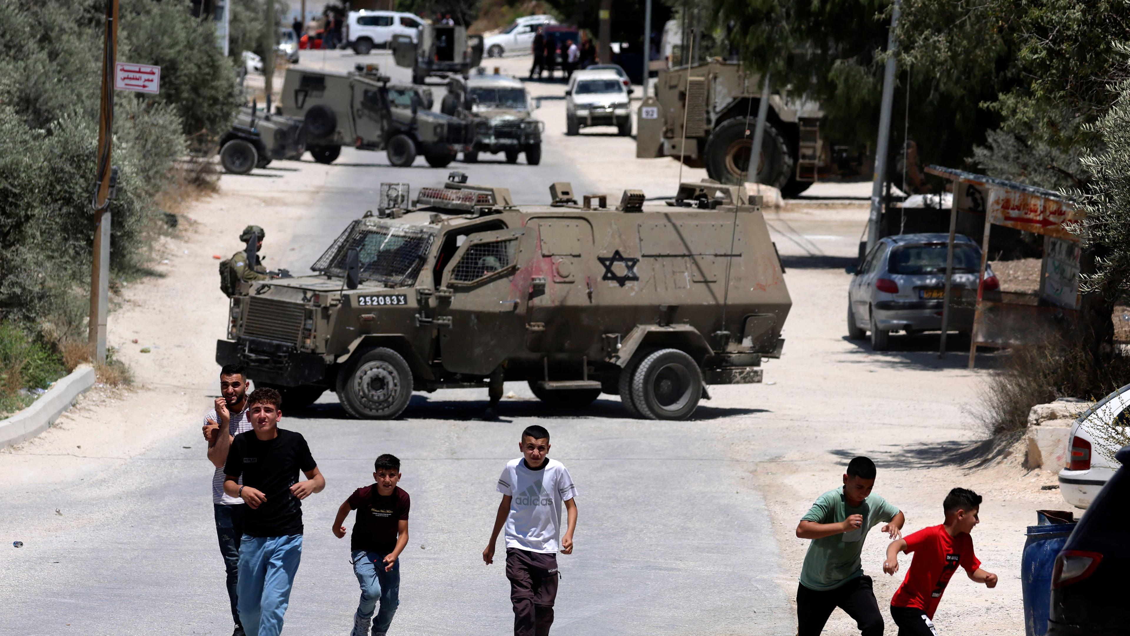 Kinder rennen, während israelische Soldaten am 29. Juni 2023 im besetzten Dorf Orif im Westjordanland, südlich von Nablus, Stellung beziehen, während sie eine Suchaktion nach gesuchten Palästinensern durchführen. 