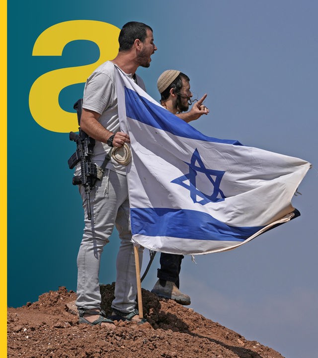 Zwei Männer neben einer israelischen Flagge, die im Boden steckt. 