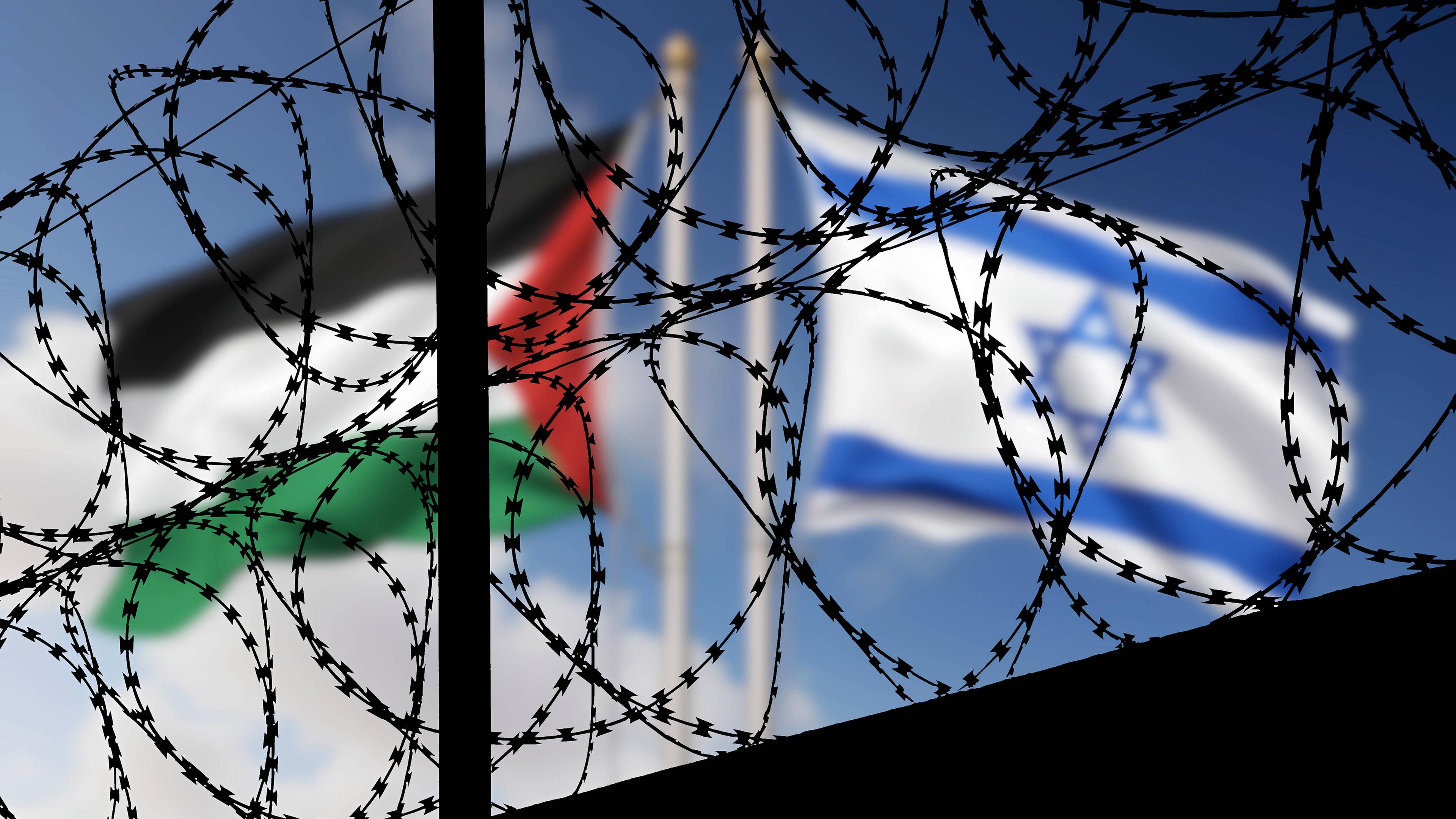 Die Flagge Israels und die palästinensische Flagge wehen im Wind, sie sind verschwommen hinter Stacheldraht zu sehen
