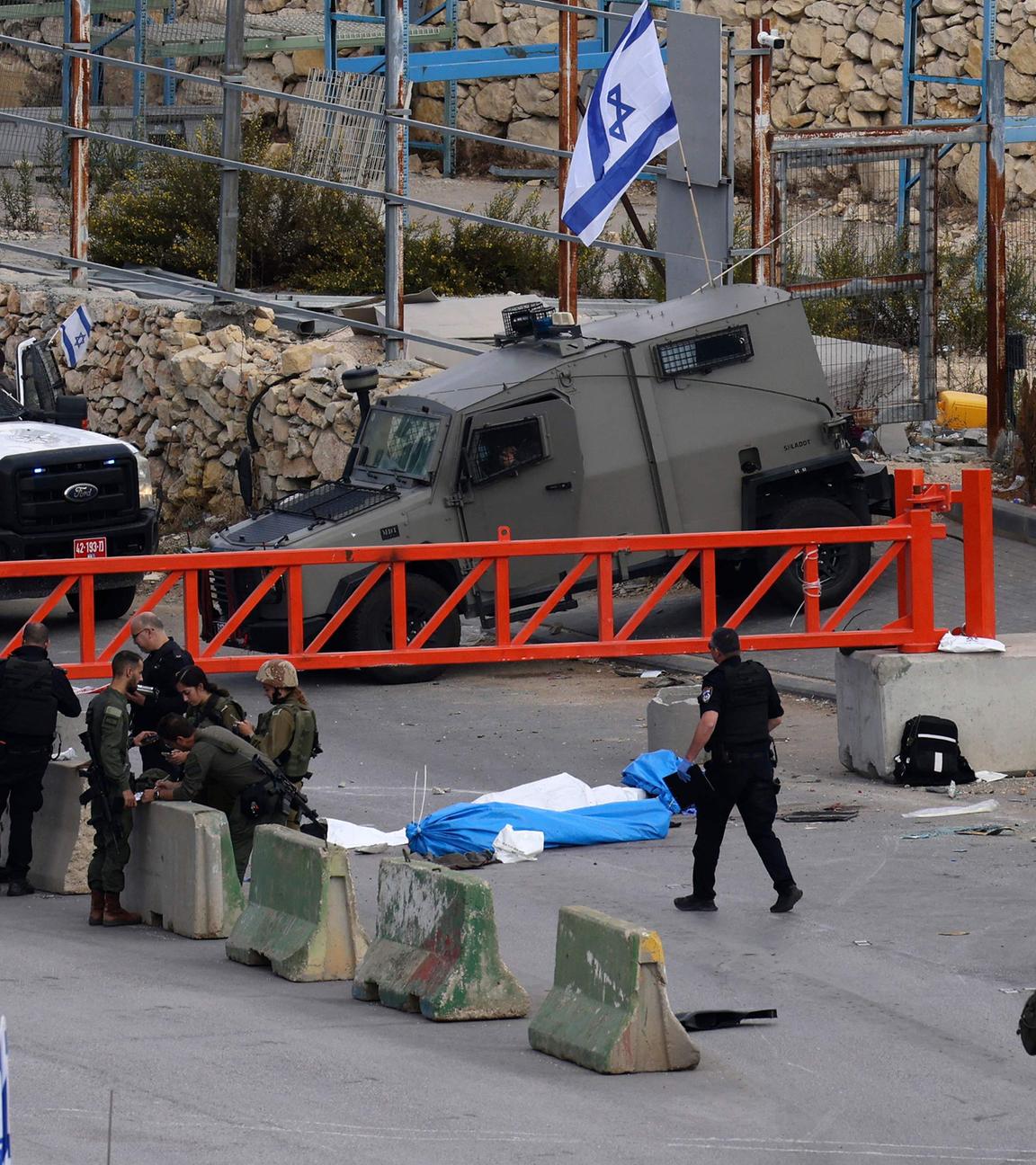 Israelische Sicherheitskräfte stehen neben den Leichen zweier palästinensischer Männer an einem Kontrollpunkt nahe Hebron