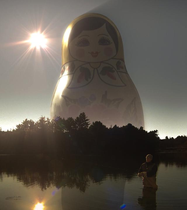 Mysterien des Weltalls: Ist Gott eine Idee von Aliens? - Russische Puppe erscheint über einem See - ein Zeichen der Mysterien des Universums.