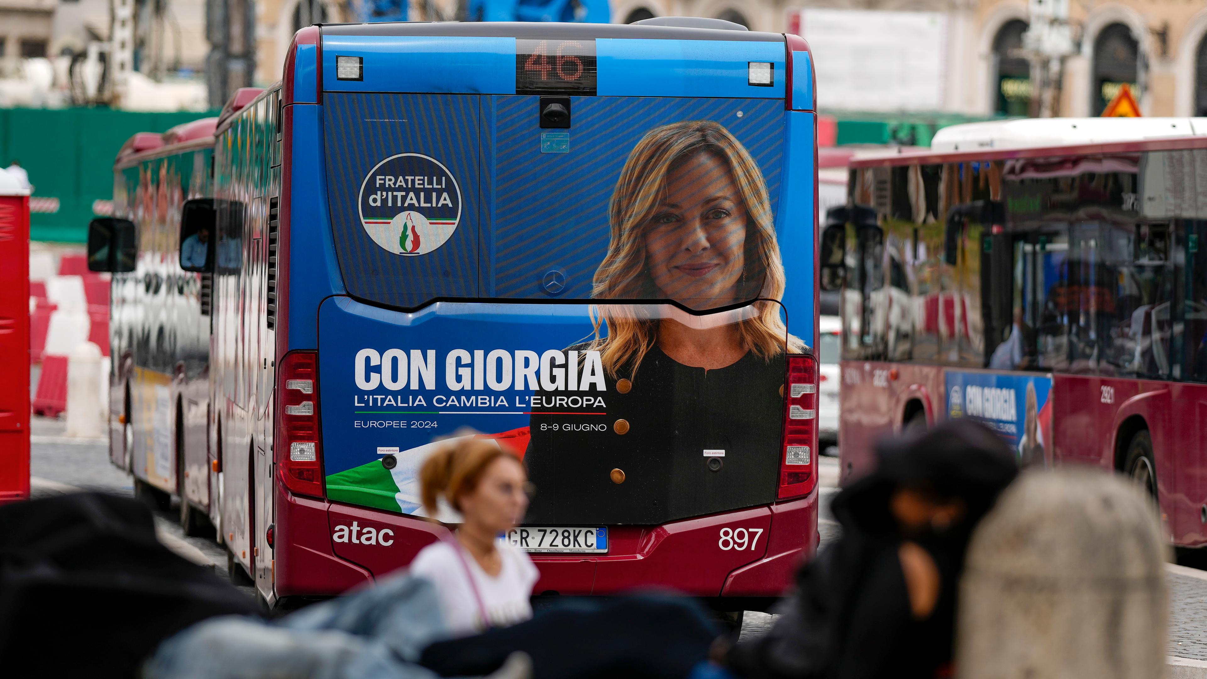 Ein roter Bus mit Wahlwerbung von Giorgia Meloni fährt durch Rom. 