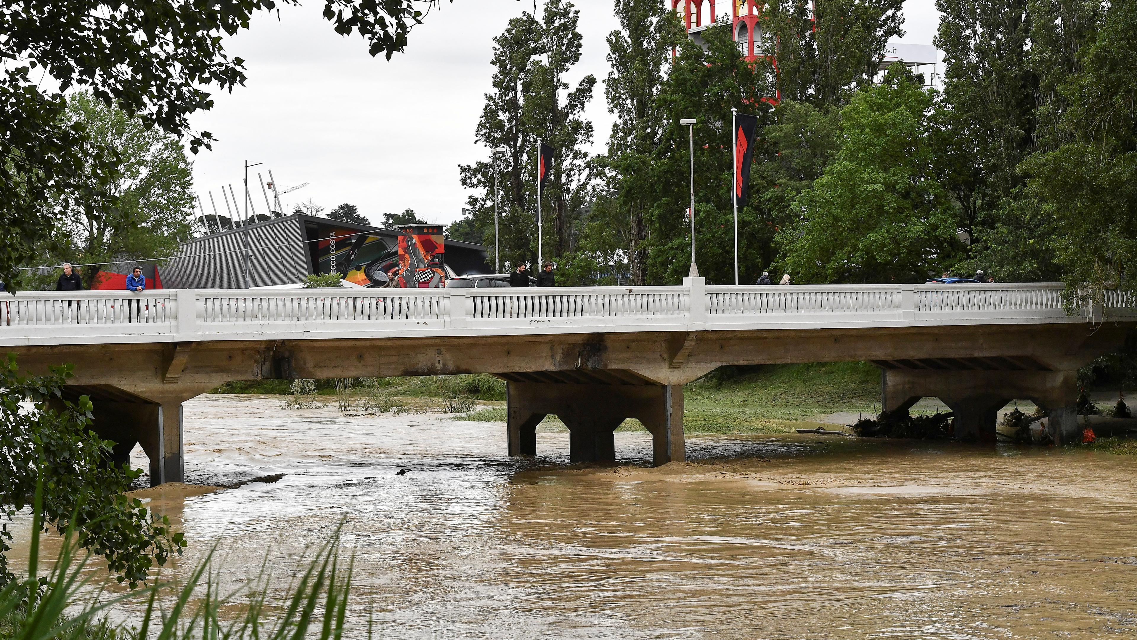 Menschen stehen auf einer Brücke, der Wasserspiegel ist wegen Starkregen angestiegen.