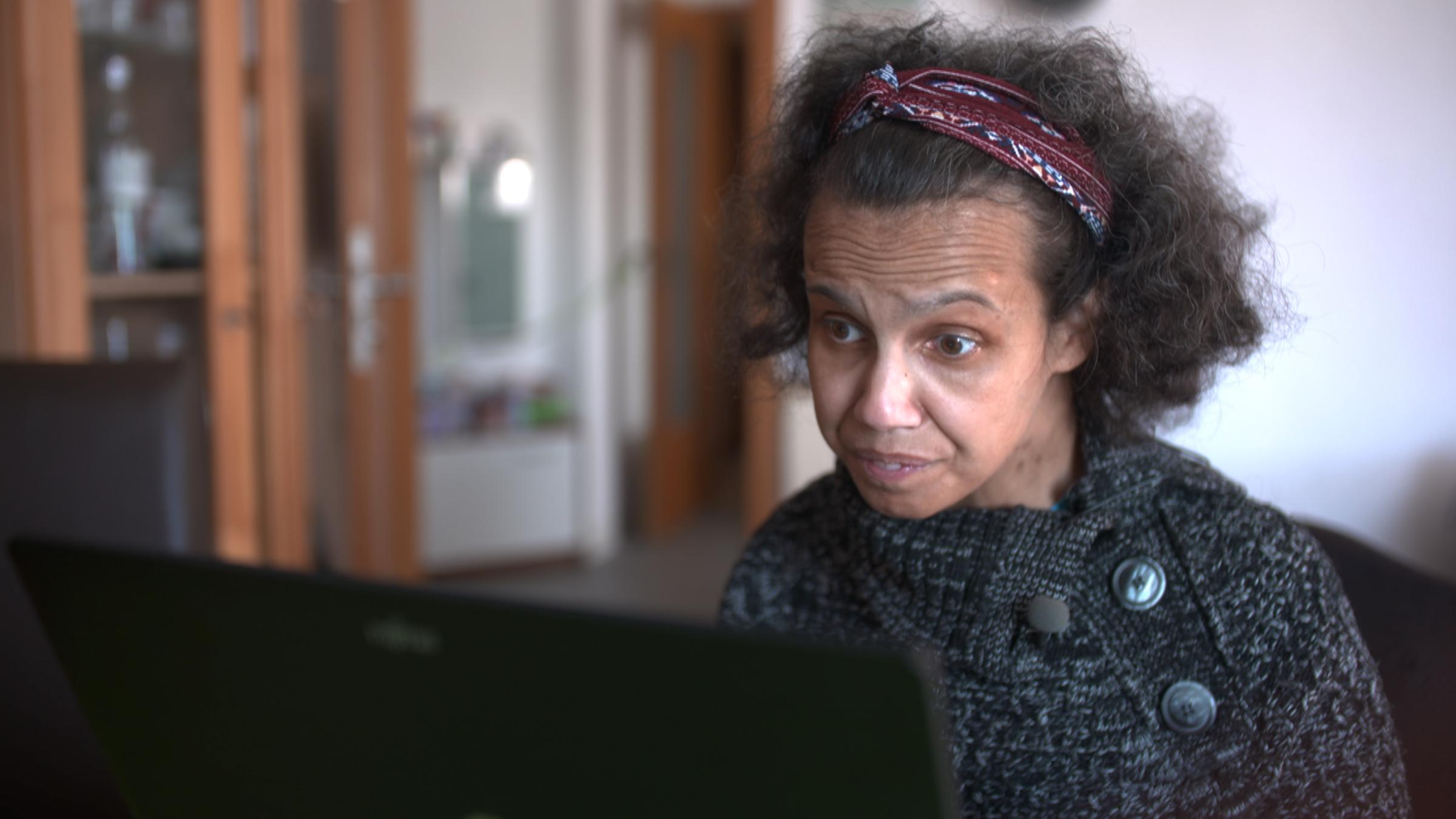 Ivonne Müller findet wegen ihrer Schwerbehinderung trotz Ausbildung und Studium keine Arbeitsstelle. Sie sitzt in ihrer Wohnung vor einem PC.
