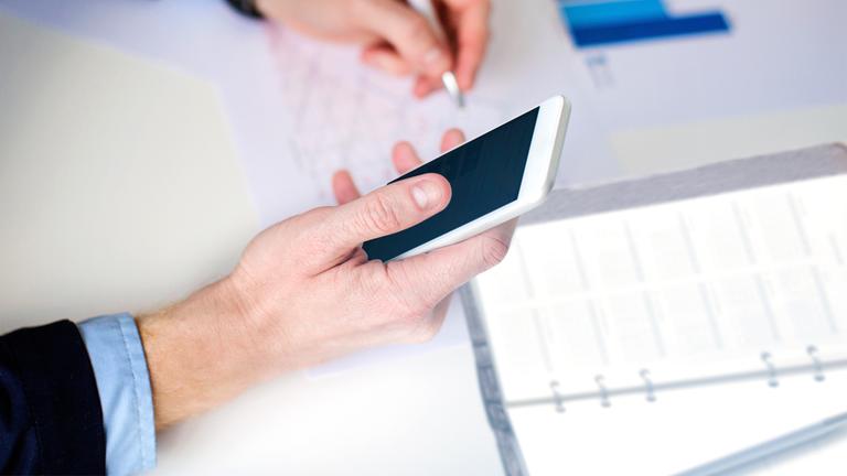 Mann benutzt Smartphone für Kalkulation