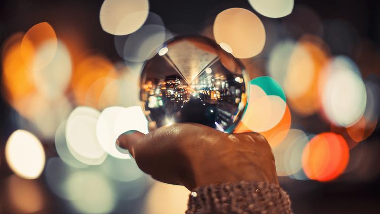 Frauenhand hält eine Kristallkugel