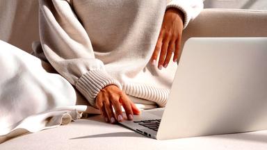 Nahaufnahme von Frauenhänden an einem Laptop
