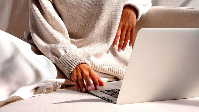 Nahaufnahme von Frauenhänden an einem Laptop