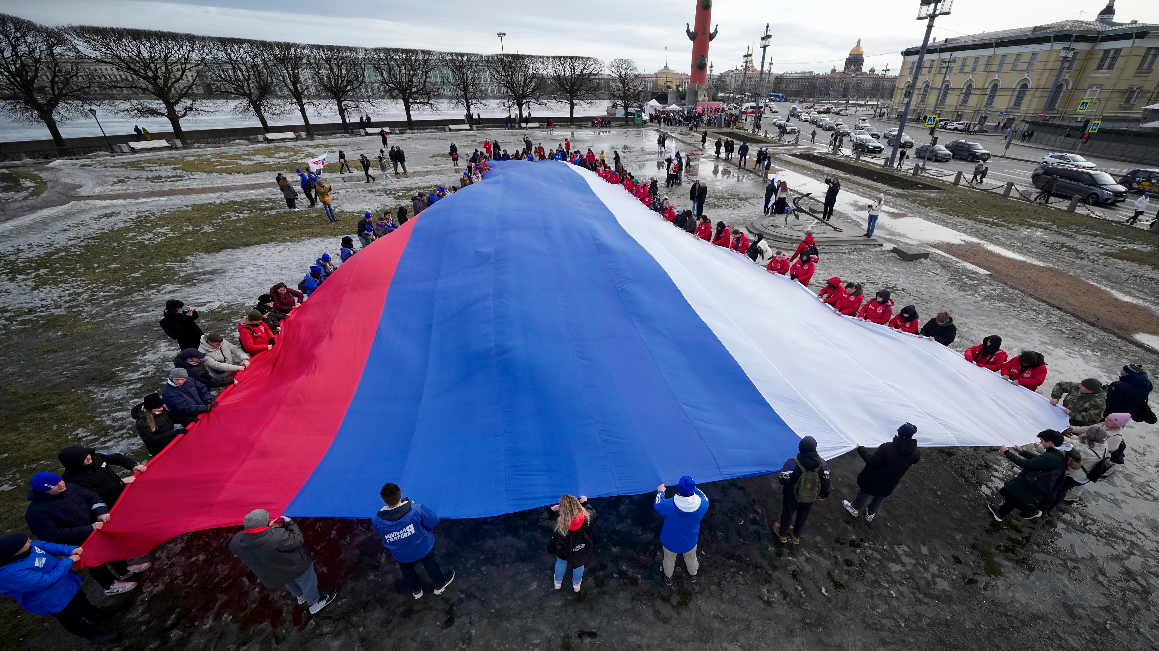 Junge Menschen entrollen eine riesige russische Flagge während einer Feier zum neunten Jahrestag der Krim-Annexion durch Russland.