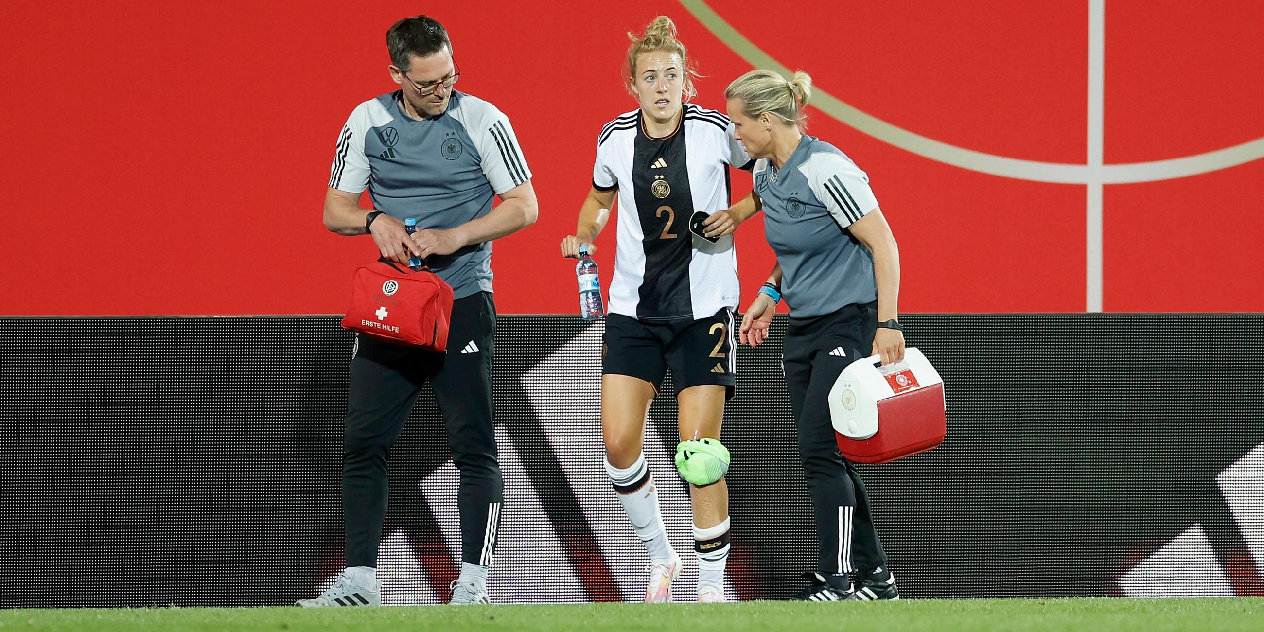 Betreuer begleiten die verletzte Carolin Simon, deren linkes Knie bandagiert ist, vom Platz beim Testspiel der DFB-Frauen gegen Sambia.