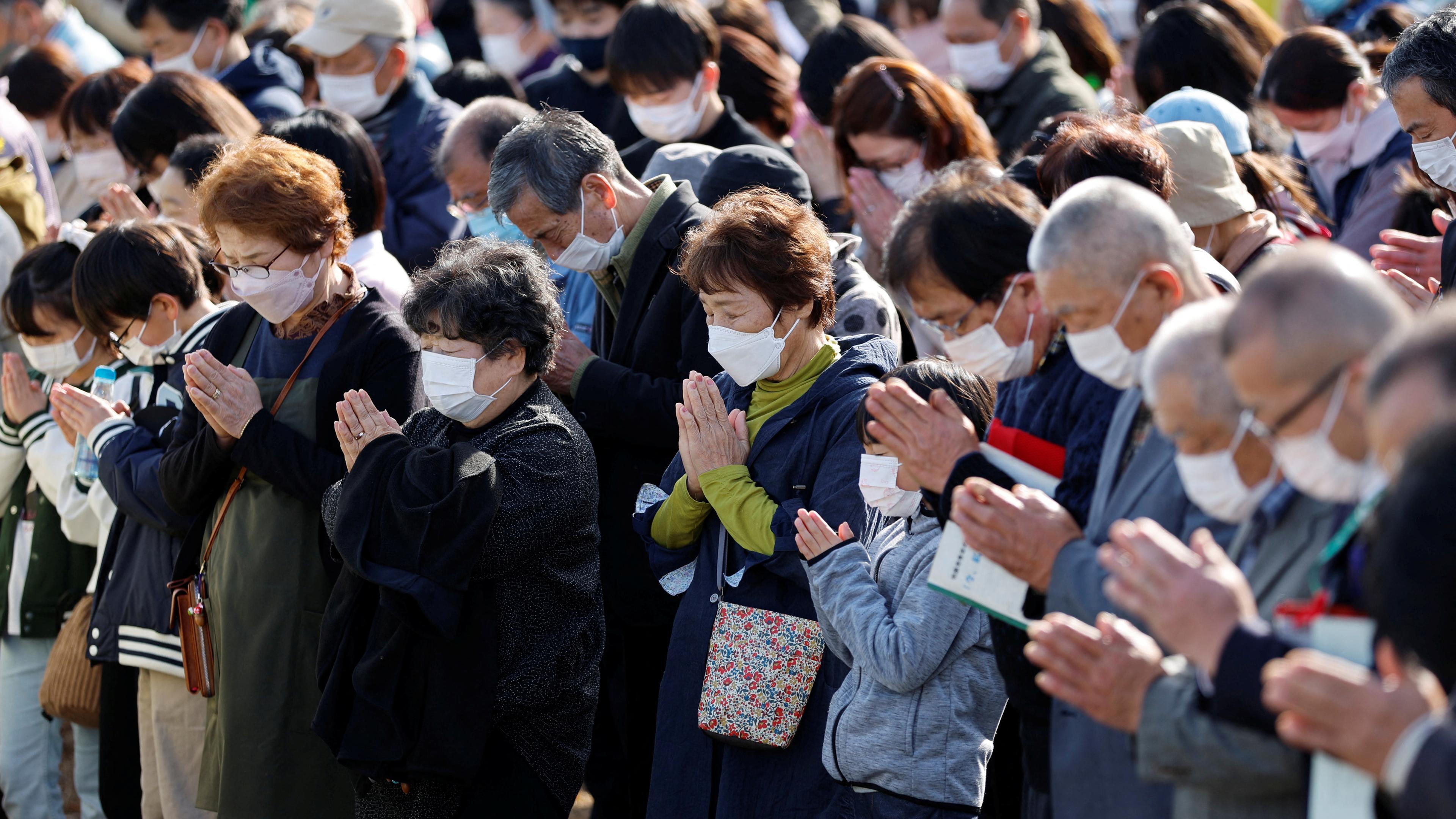 Japan, Fukushima: Menschen beten während einer Schweigeminute zum Jahrestag der Reaktorkatastrophe in Fukushima