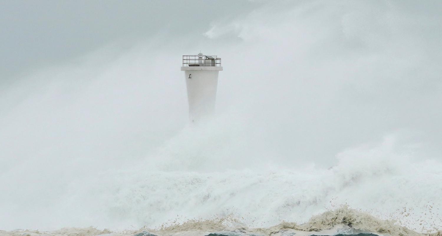 Wellen schlagen gegen die Mole und einen Leuchtturm im Hafen von Kiho