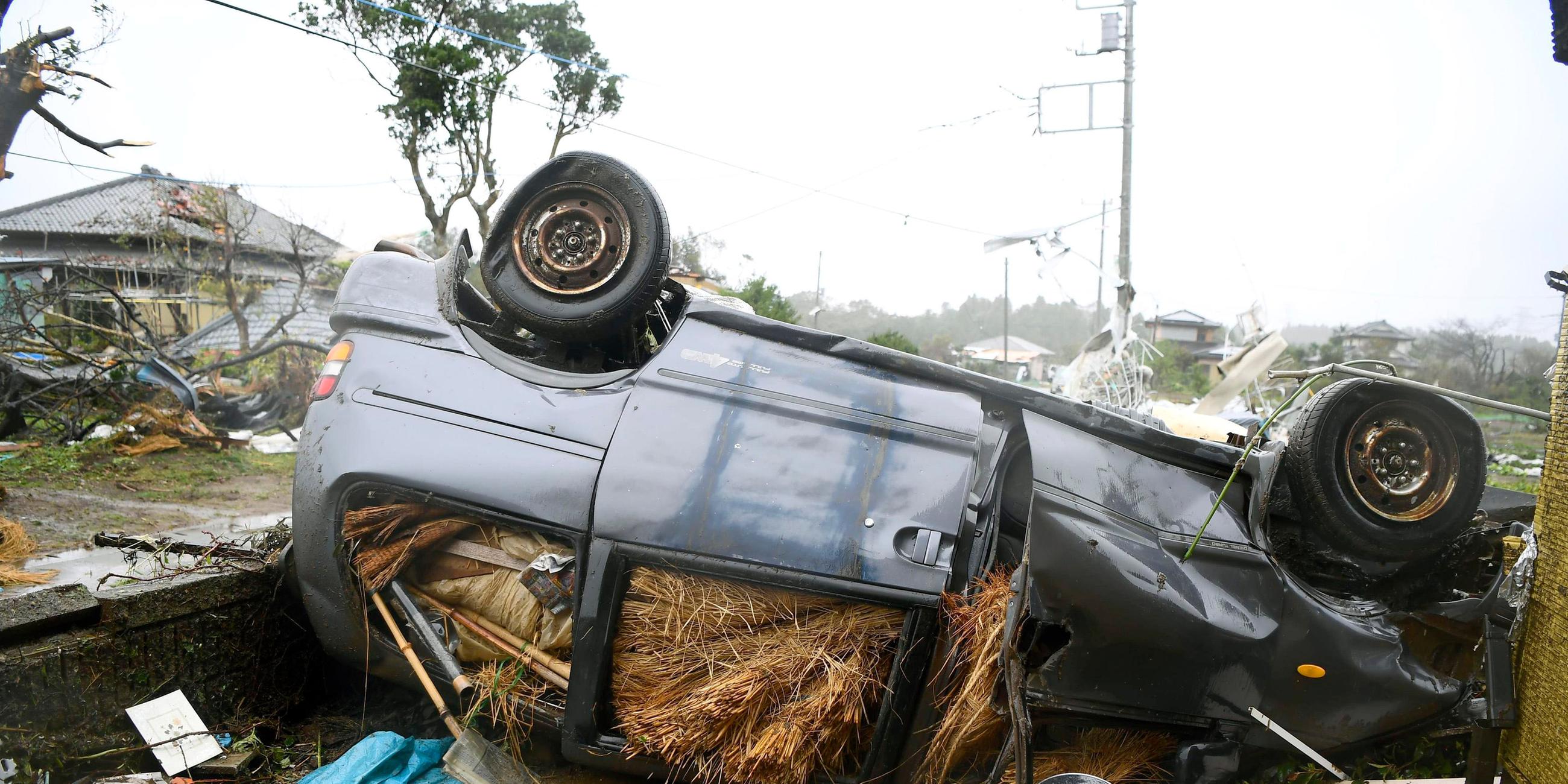 Ein durch den Sturm umgestürztes Auto liegt in Ichihara