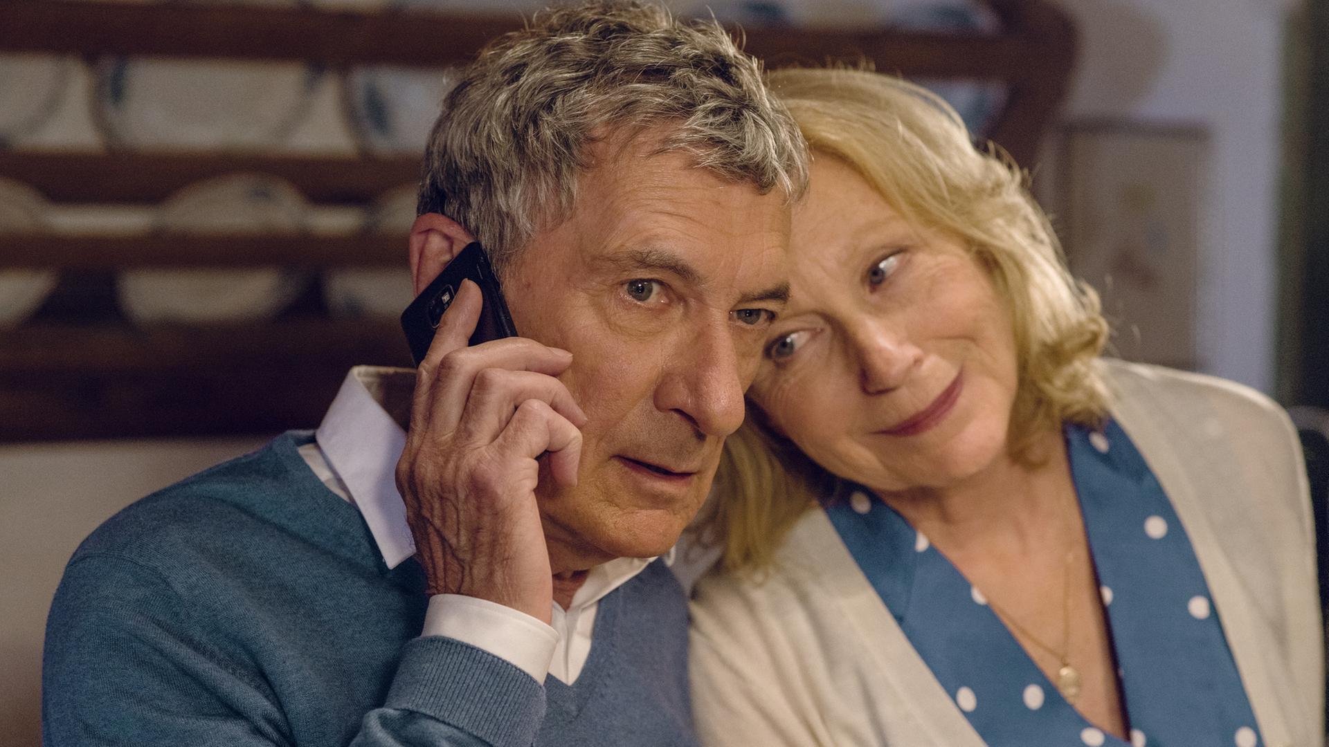 "Jella jagt das Glück": Jella (Maren Kroymann) lehnt ihren Kopf an Klaus (Rudolf Kowalski) Kopf. Klaus hält sein Handy am 