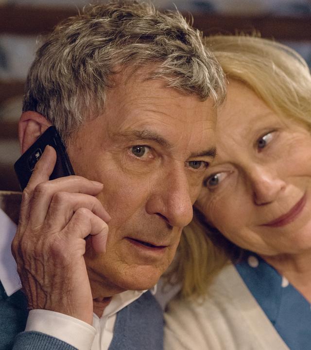 "Jella jagt das Glück": Jella (Maren Kroymann) lehnt ihren Kopf an Klaus (Rudolf Kowalski) Kopf. Klaus hält sein Handy am 